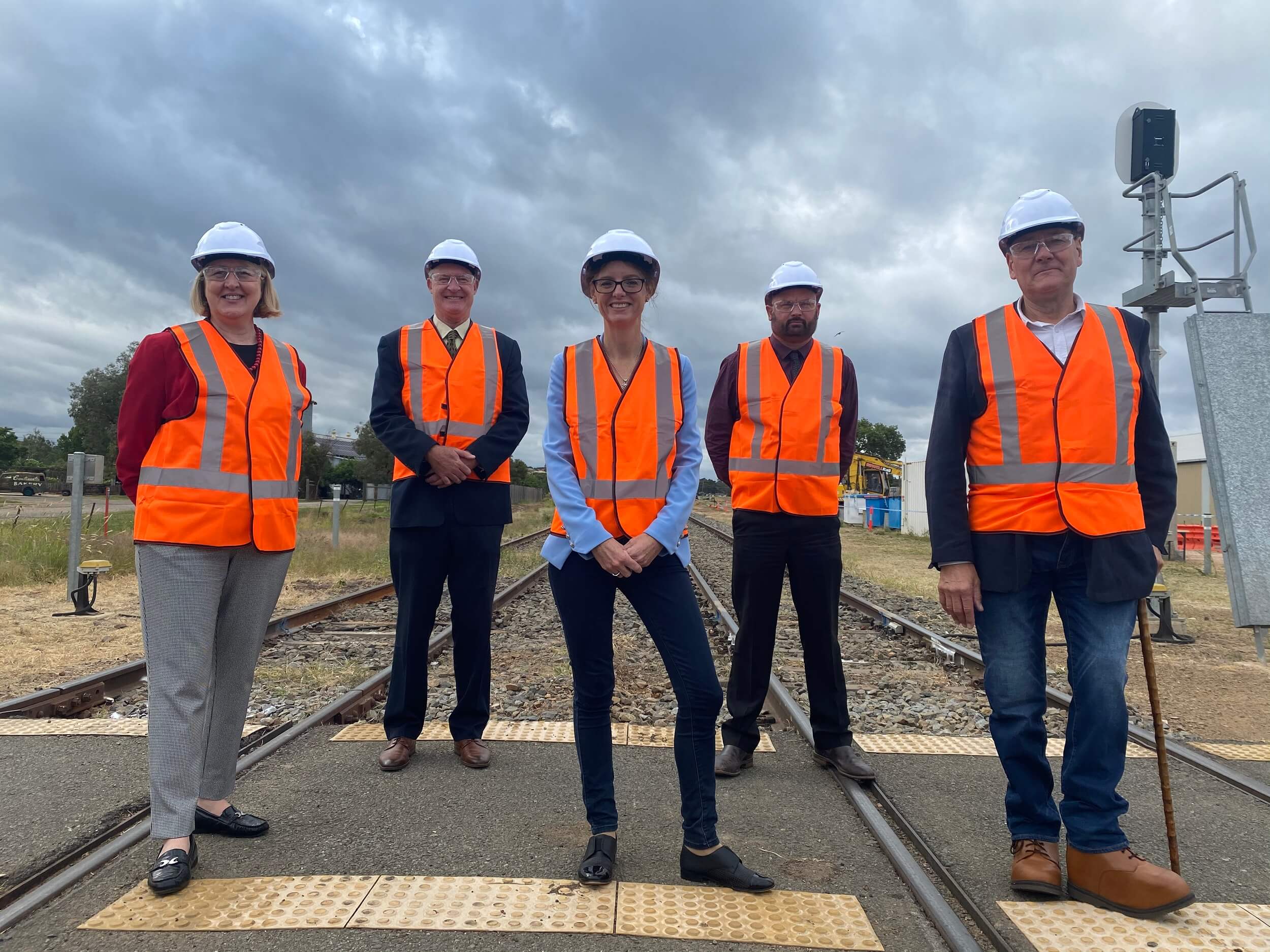 Sam Knight, Luke Taberner, Steph Cooke MP, Cole Davis Neil Smith stand on railway lines, wearing high vis vests and hard hats.