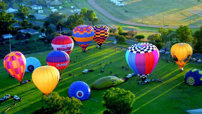 Brightly coloured hot air balloons on a green field. 