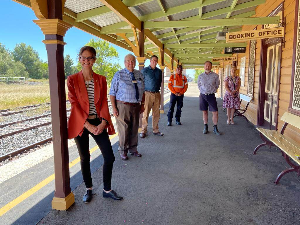 Steph Cooke stands with five people on a railway platform.