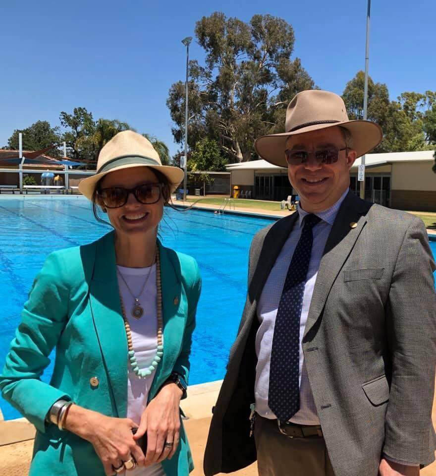 Steoh Cooke and Rick Firman wear hats and sunglasses, they stand in front of a large swimming pool.